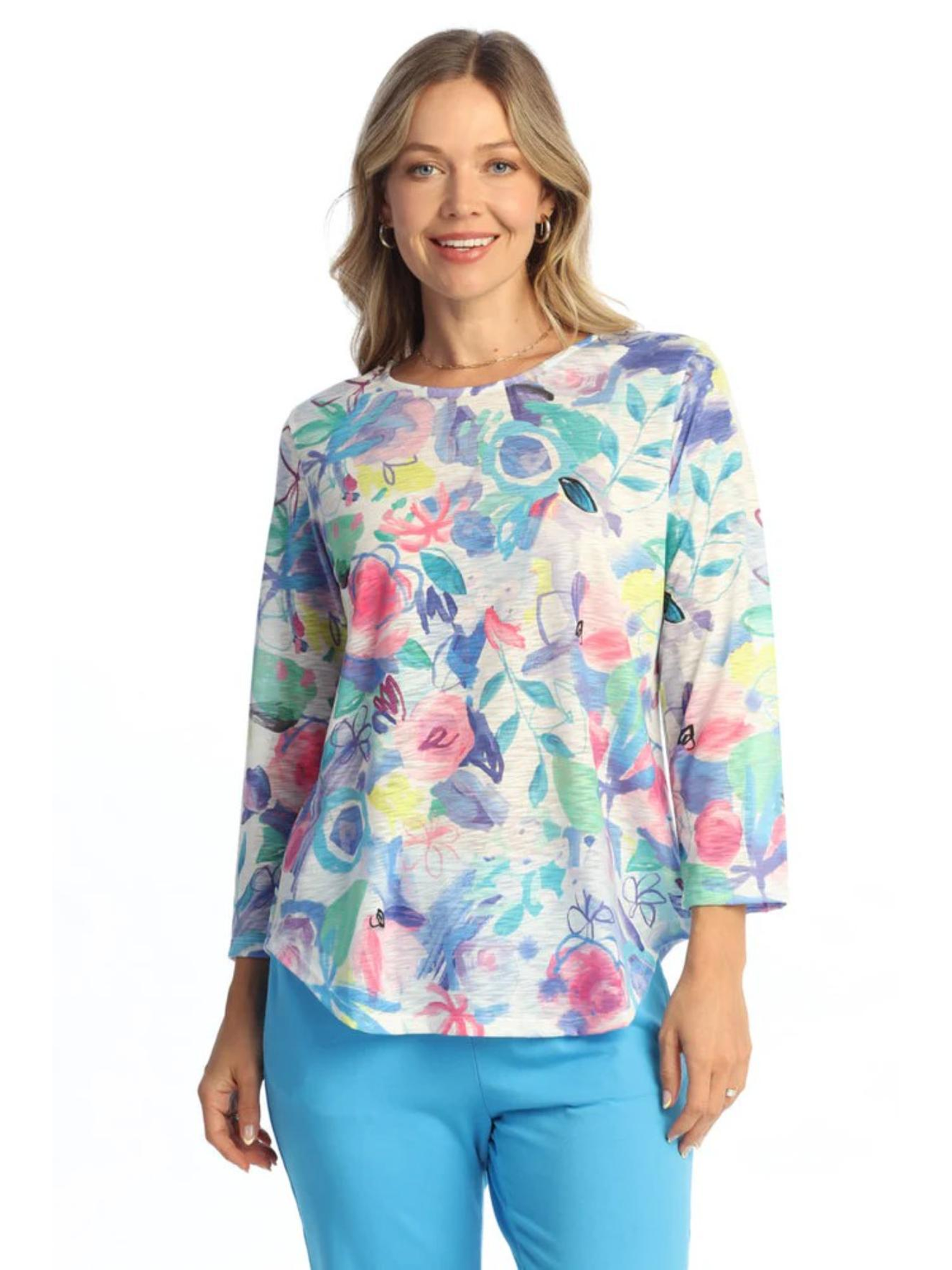 Woman wearing a colorful floral blouse with blue pants on a white background