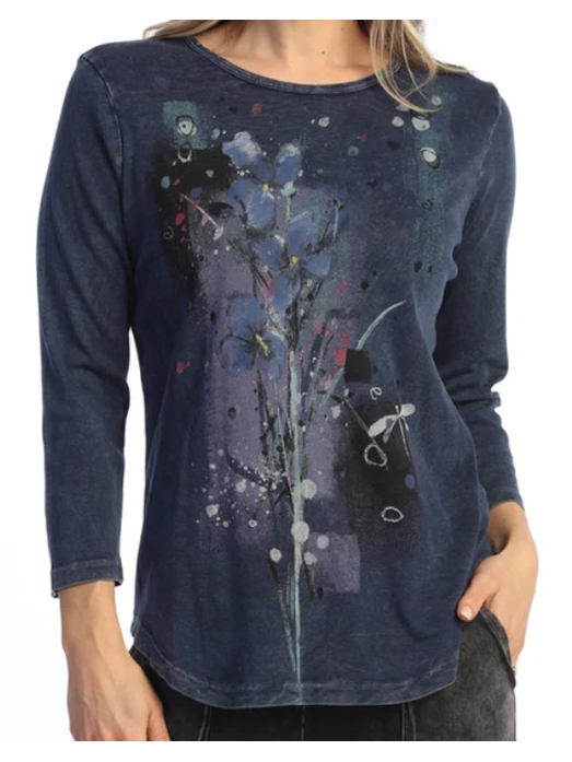 A woman wearing a dark blue long-sleeve t-shirt with an abstract floral and paint-splatter graphic on the front, set against a plain white background.