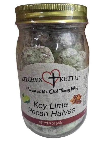 A glass jar of Kitchen Kettle Key Lime Pecan Halves filled with green pecan halves, set against a background of cardboard boxes.