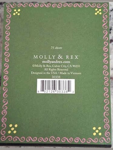 Green notebook with decorative border and branding on a marble surface