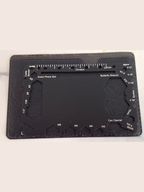 Black multi-tool card with various measurements and tools on a marble surface