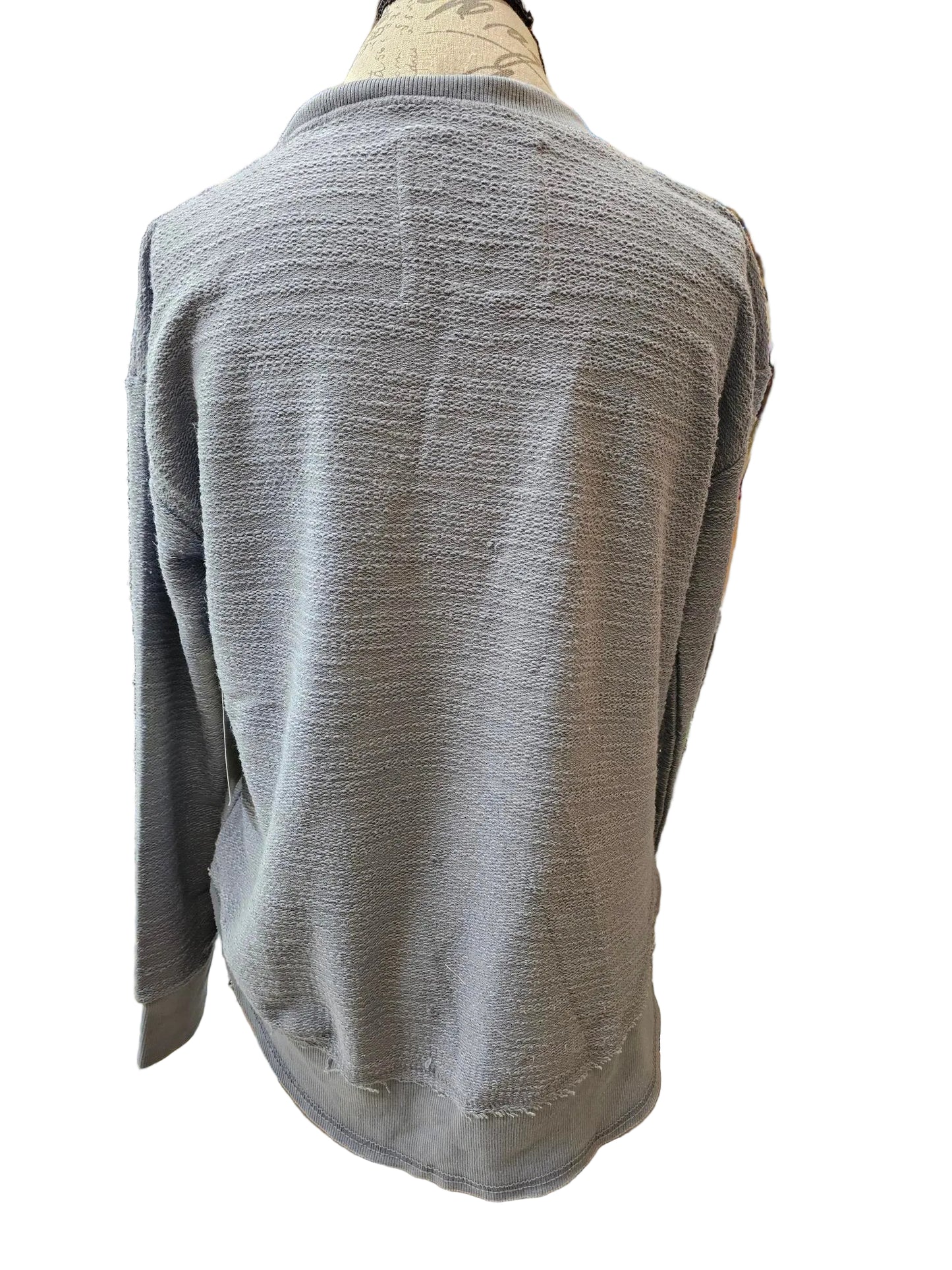A light gray textured knit cardigan sweater draped over a mannequin torso in a retail store setting.