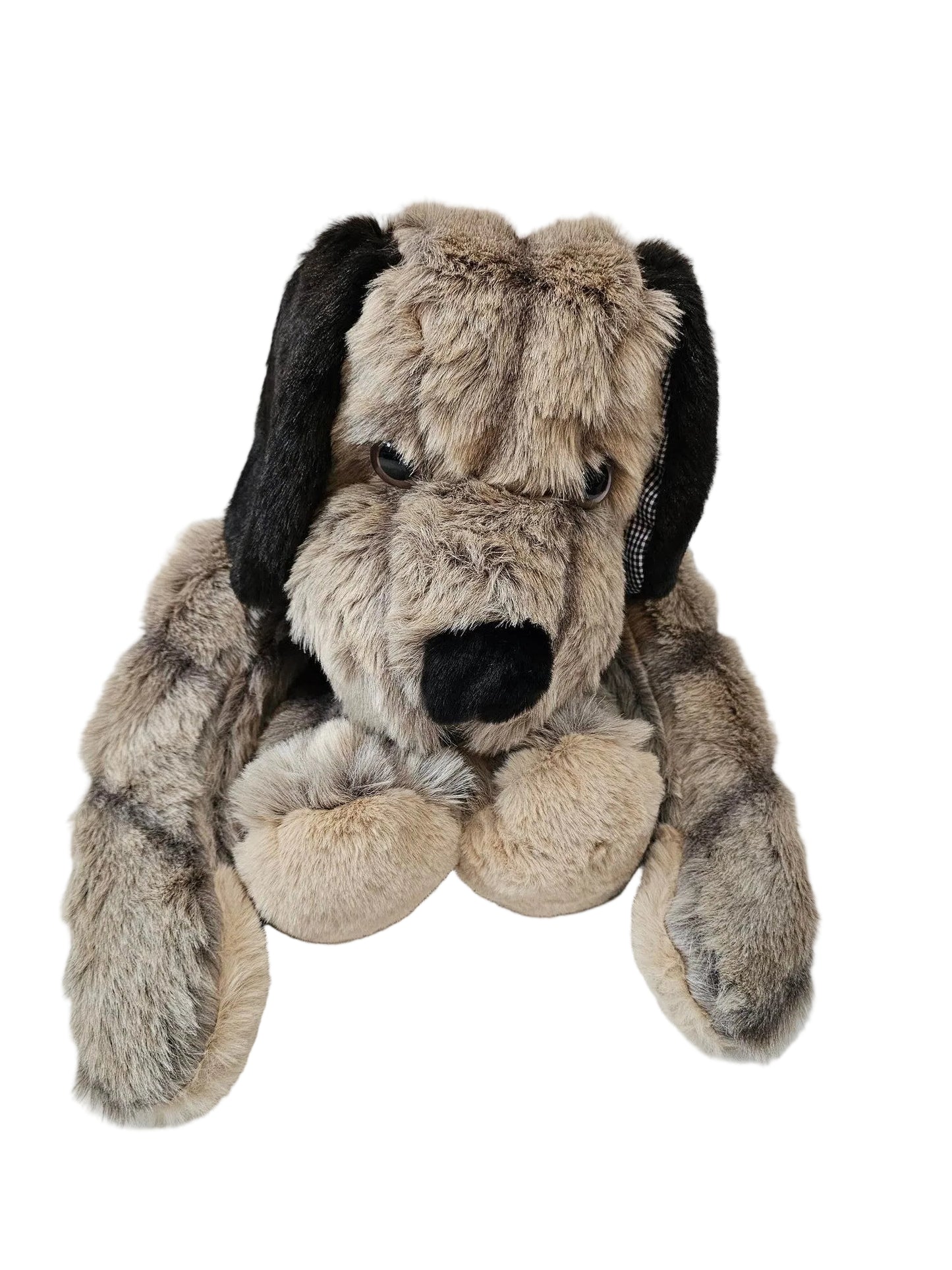 A plush dog toy with a shaggy gray and beige fur pattern, black floppy ears, and a black nose, sitting on a white surface against a white paneled wall.
