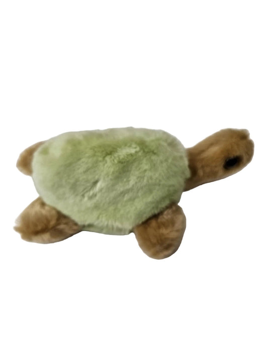 A small plush sea turtle toy with a light green fuzzy shell and brown fuzzy head, flippers, and legs, lying on a plain light surface.