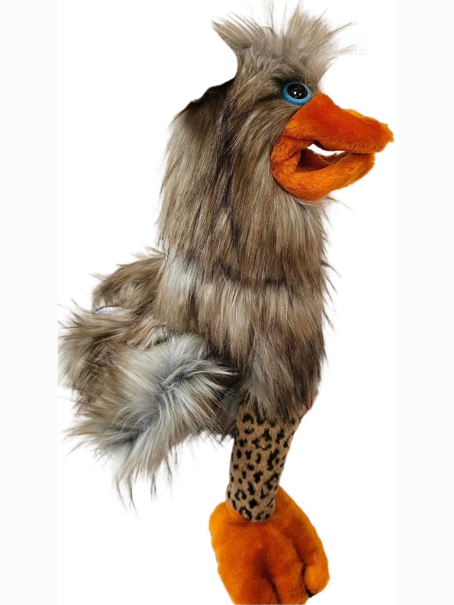 A plush toy bird with fluffy gray and brown feathers, bright orange beak and feet, and a spotted leopard-print leg, being held by a human hand against a white paneled background.