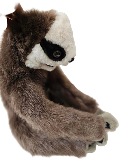 A plush sloth toy with brown and white fur, held by a hand against a white background.