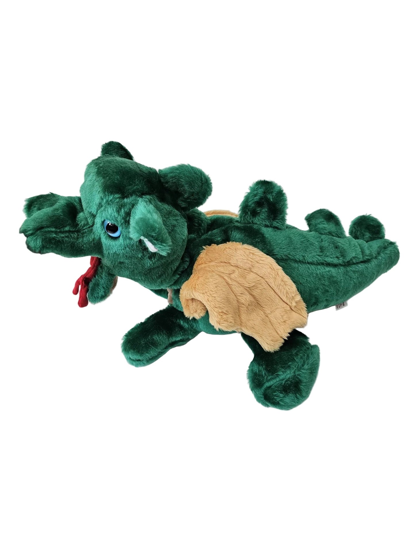 A green plush dragon toy with tan wings and a small red tassel, shown on a white surface with a hand holding its head.