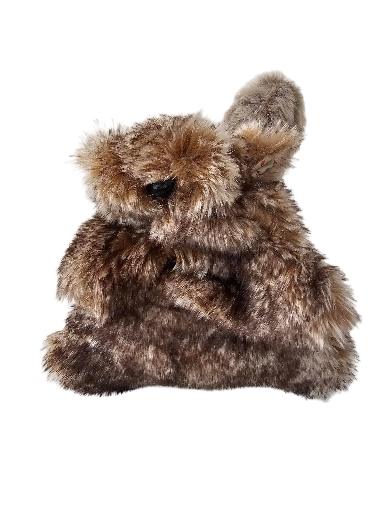 A plush faux fur squirrels toy in shades of brown and beige, sitting on a white surface against a white paneled wall.