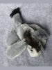 A small gray plush toy or stuffed animal with a black-tipped tail, photographed on a soft gray textured background.