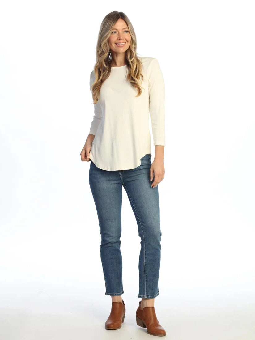 Woman wearing a white sweater, blue jeans, and brown boots on a white background