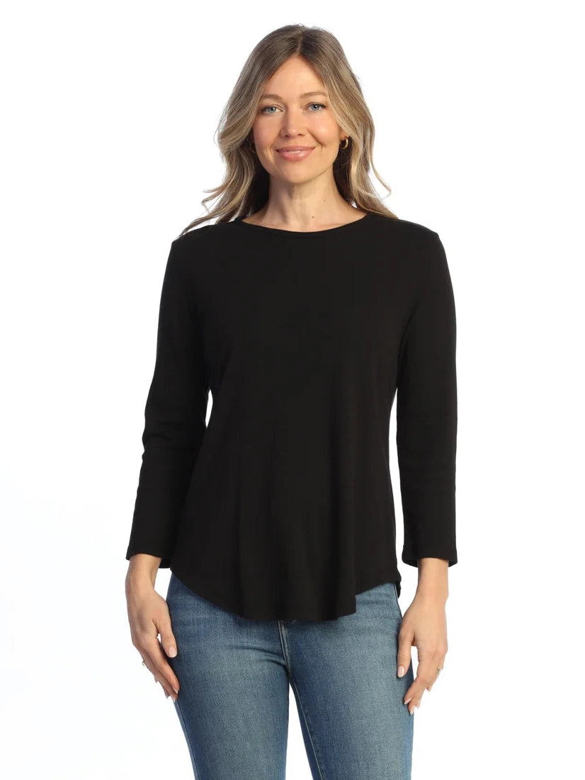 Woman wearing a black long-sleeve top and blue jeans on a white background