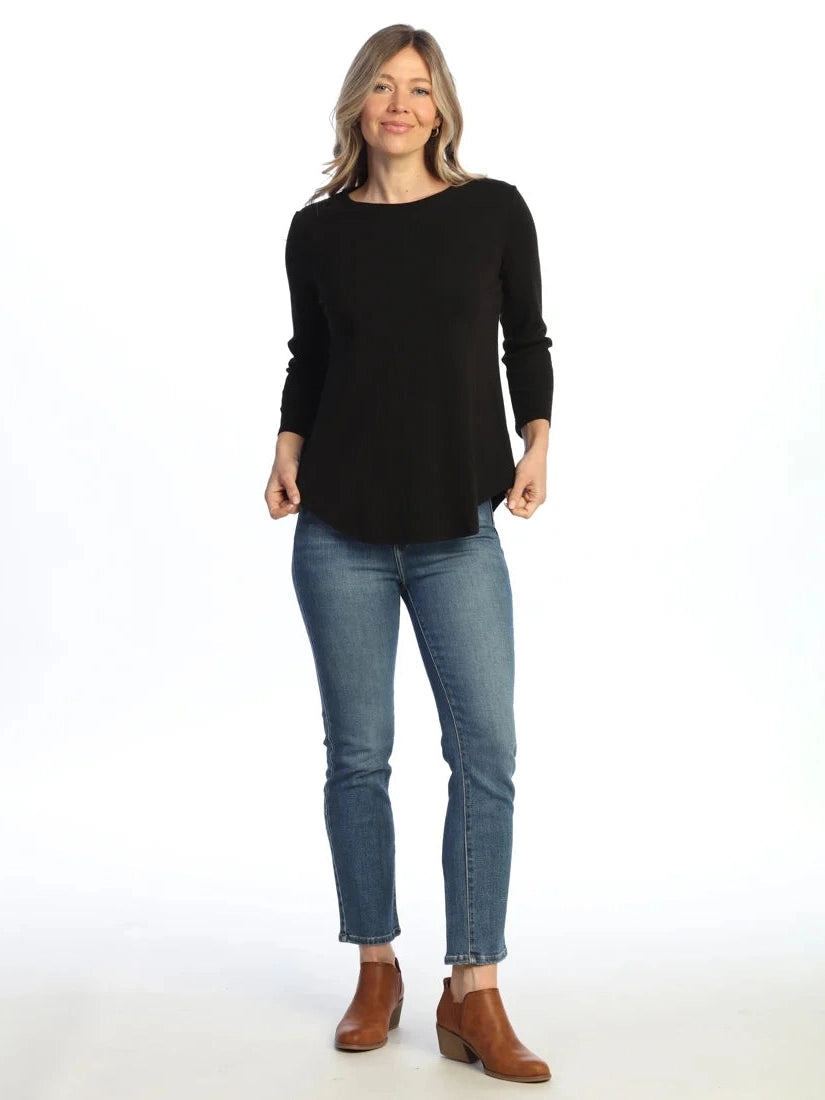 Woman wearing a black long-sleeve top and blue jeans on a white background