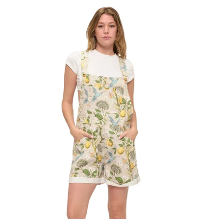 Woman wearing a floral overalls and white t-shirt on a plain background