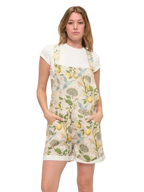 Woman wearing a floral overalls and white t-shirt on a plain background