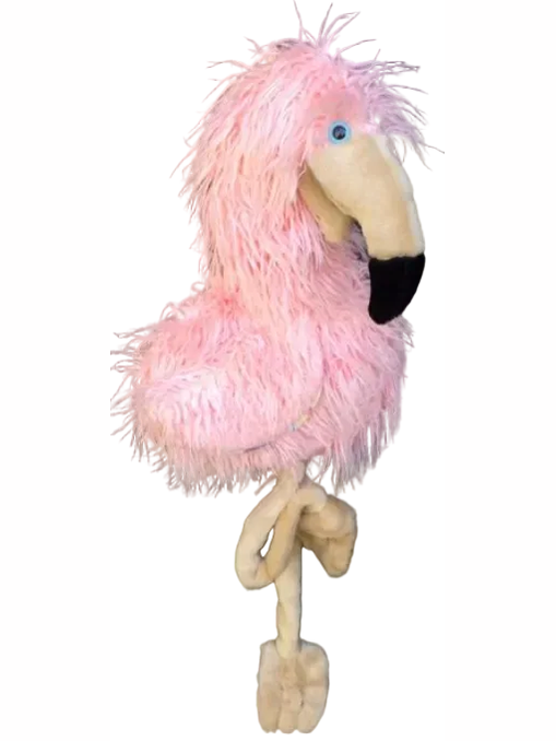 A fluffy pink flamingo plush toy with a beige beak, black-tipped beak, blue eye, and tan legs, hanging against a black wire grid background.