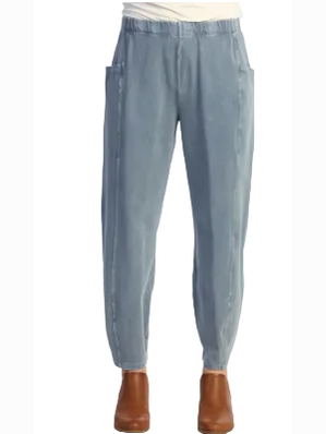 Light blue denim pants with a relaxed, tapered fit and side pockets, shown on a model from the waist down wearing brown ankle boots against a white background.
