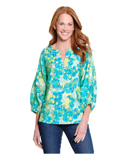 Woman wearing a floral blouse with blue and green pattern on a white background