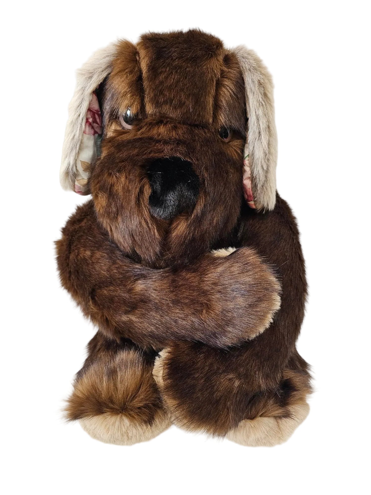 A brown faux fur dog costume or plush toy with a white and gray faux fur collar, shown against a white paneled wall.