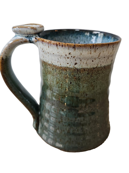 Handmade ceramic mug with a textured surface on a speckled countertop.
