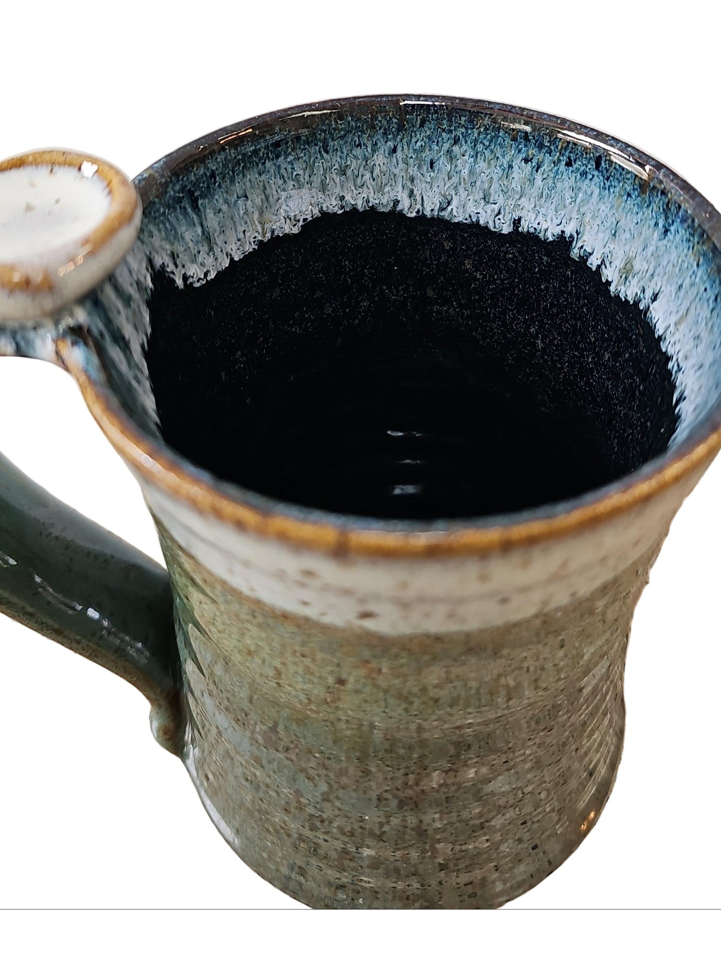 Ceramic mug with blue interior and speckled exterior on a speckled surface.